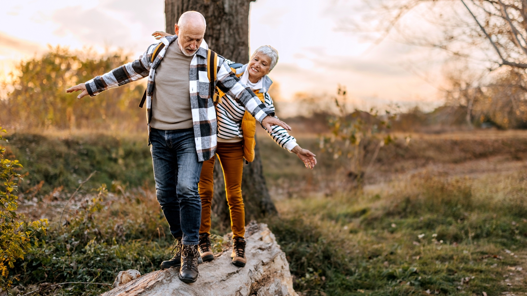 Senior couple walking on a tree log